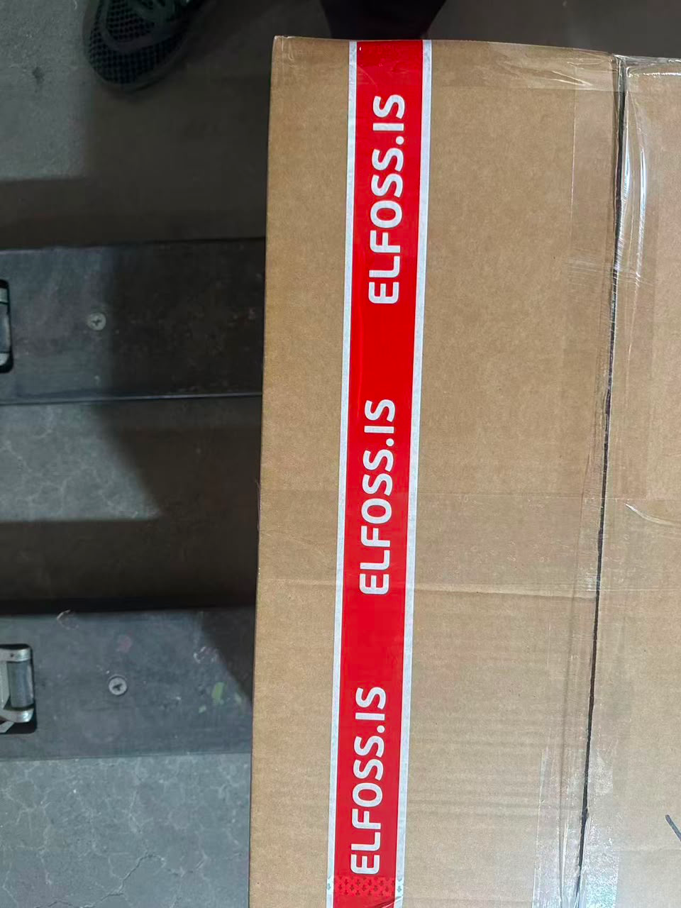 Red ELFOSS.IS custom printed packing tape with white lettering applied to a brown shipping carton