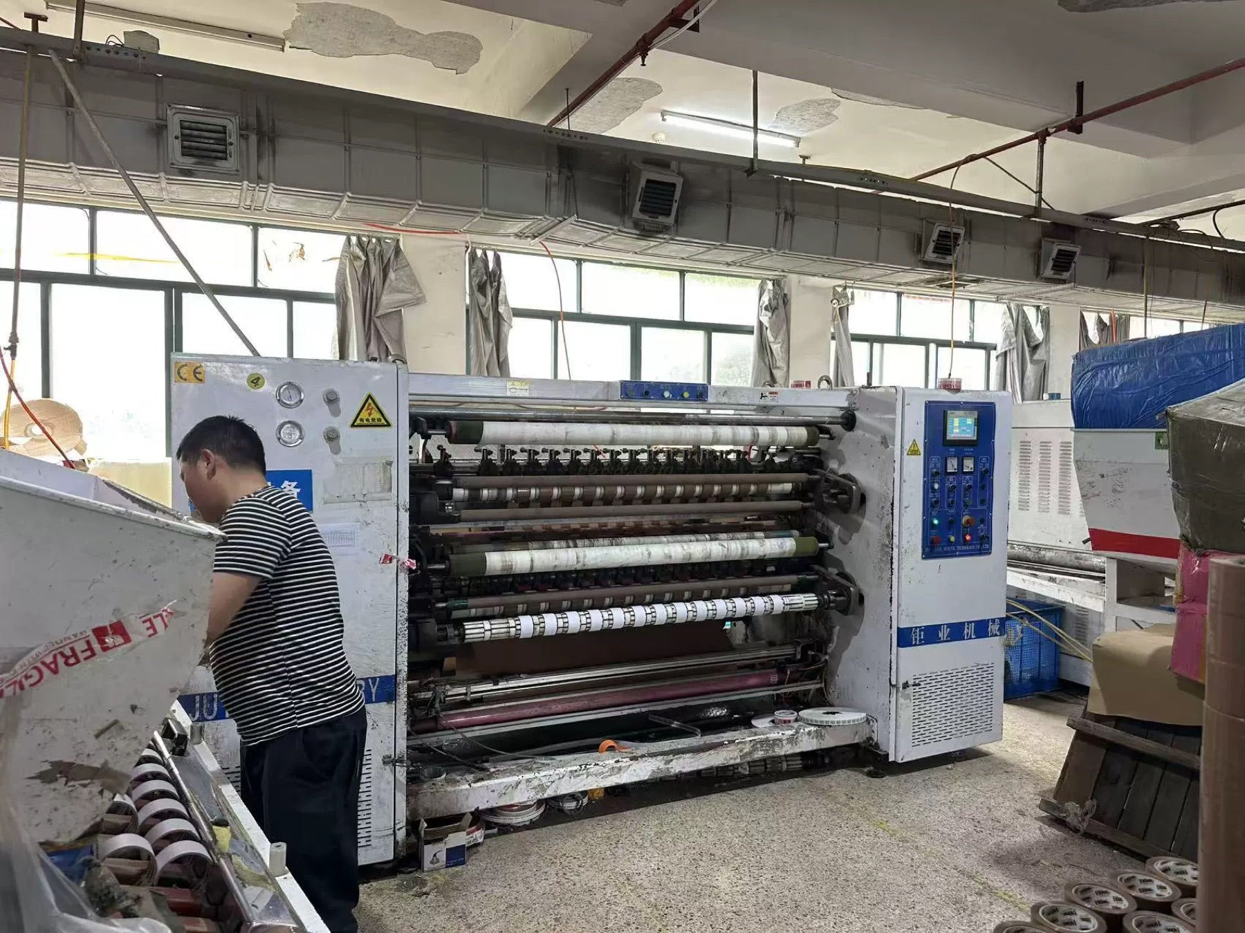 Factory worker operating tape slitting machine