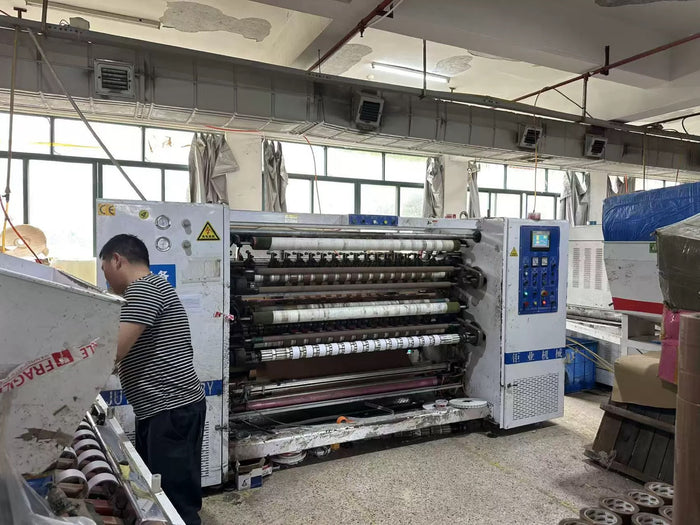 Factory worker operating tape slitting machine
